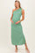 woman wearing a green one-shoulder maternity maxi dress and gently holding her baby bump