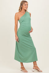 woman wearing a green one-shoulder maternity dress that accentuates her baby bump