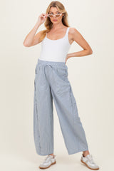 woman wearing a white tank top and light blue striped maternity pants with an elastic waistband and sneakers