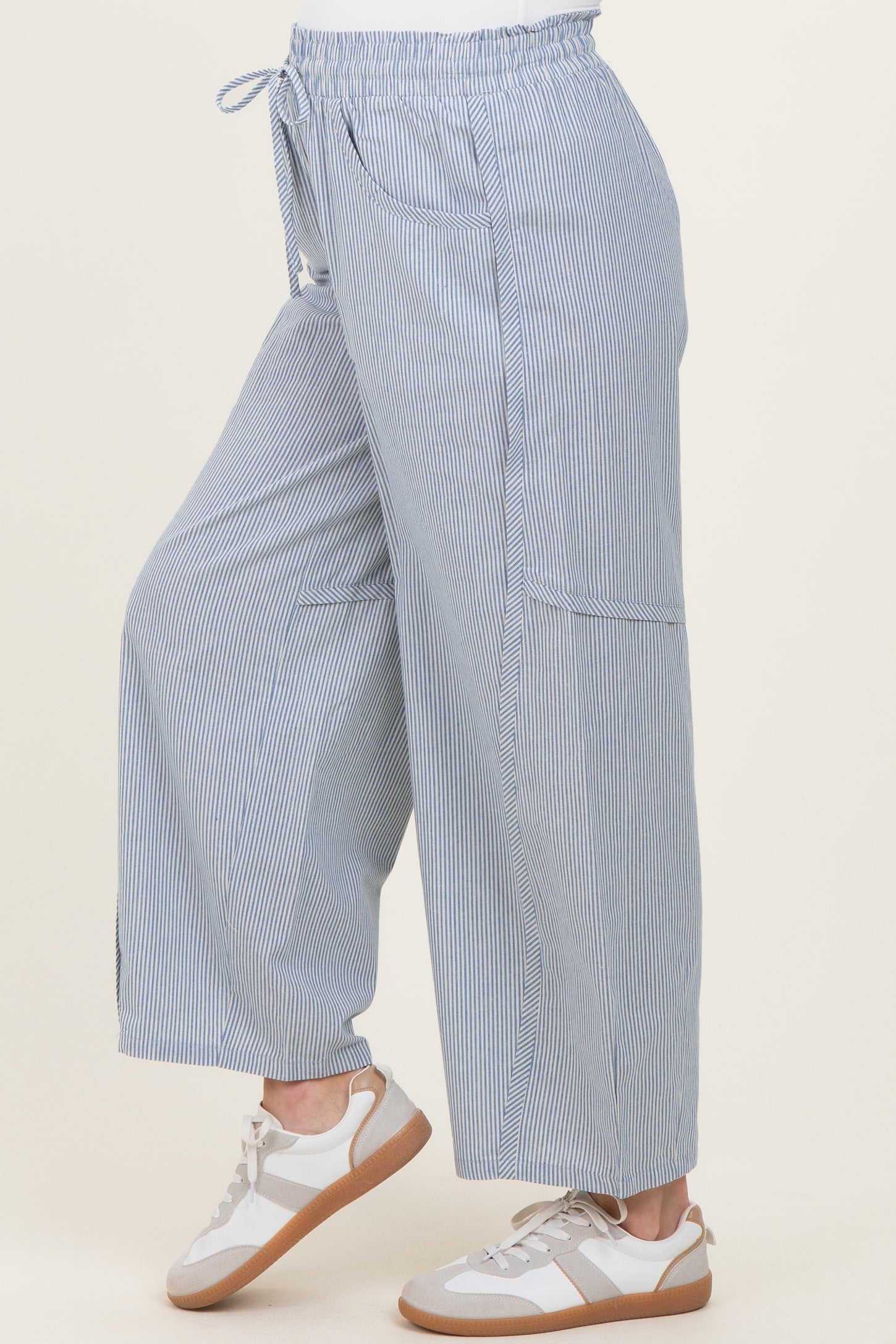 woman wearing light blue and white striped maternity wide-leg pants with drawstring waist and side pockets.
