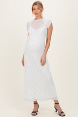 woman wearing a white lace cap sleeve maternity dress with a floor-length hem and a relaxed fit