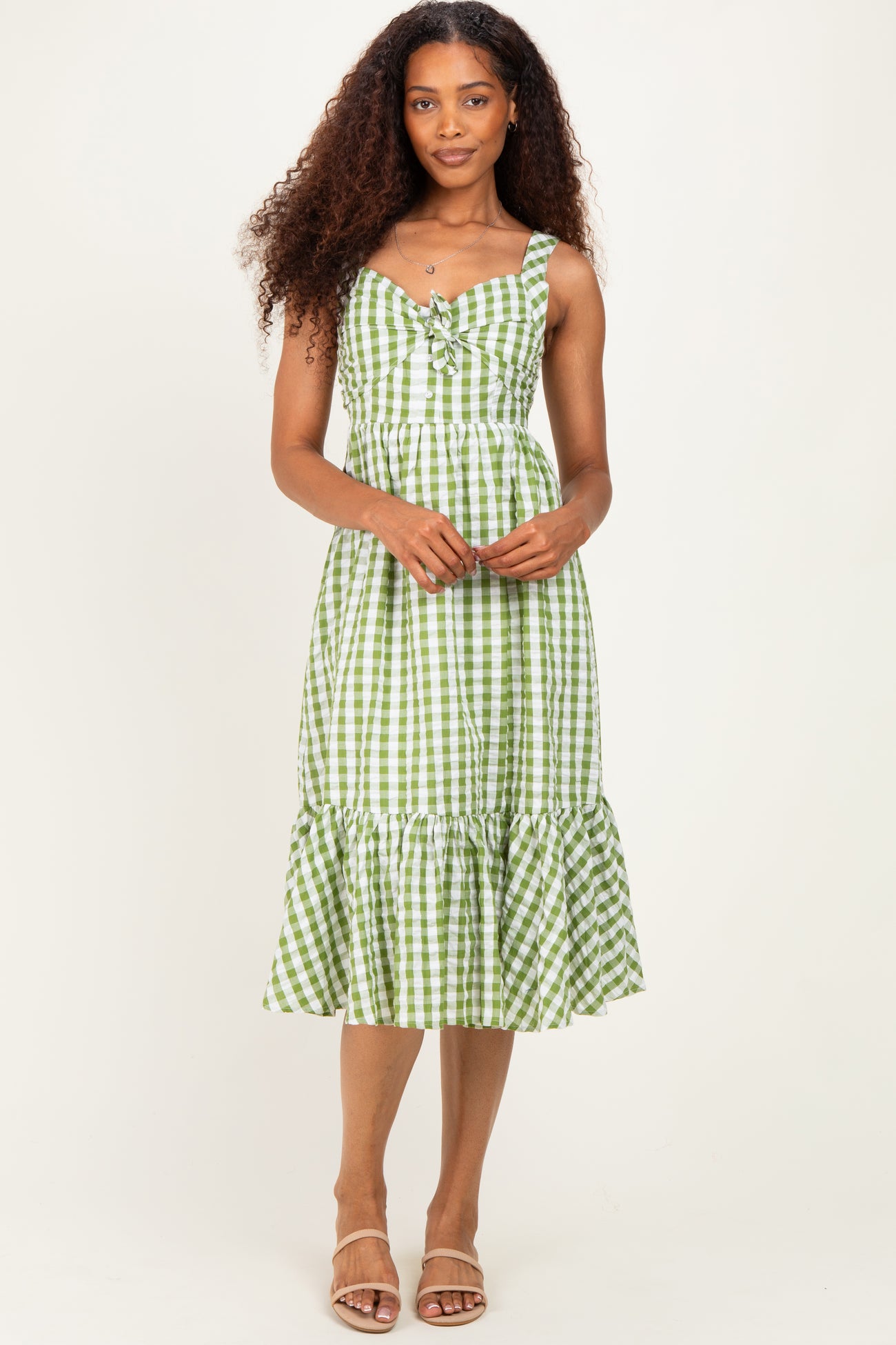woman wearing a green and white gingham midi dress with a tiered ruffle hem and adjustable straps