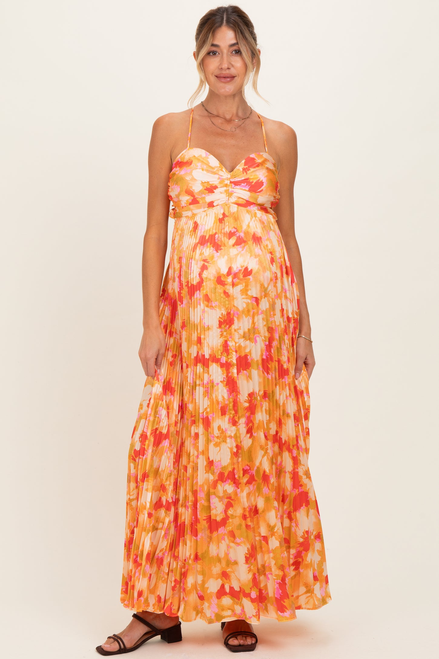 woman wearing a floral pleated maternity maxi dress with a sweetheart neckline and a visible baby bump