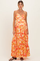 woman wearing a floral pleated maternity maxi dress with a sweetheart neckline and a visible baby bump