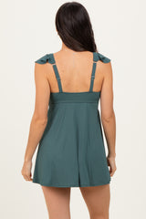 woman wearing a teal sleeveless dress with ruffled straps, showing a back view
