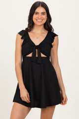 woman wearing a black ruffled sleeve dress with a front tie and cutout details