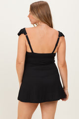 woman wearing a black maternity swim dress with ruffled straps and a fitted bodice, showing her back