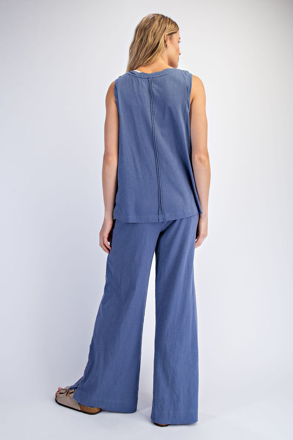 woman wearing a casual sleeveless blue top and matching wide-leg pants, viewed from the back