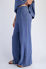 woman wearing navy blue wide-leg pants with a relaxed fit and button detail at the hem