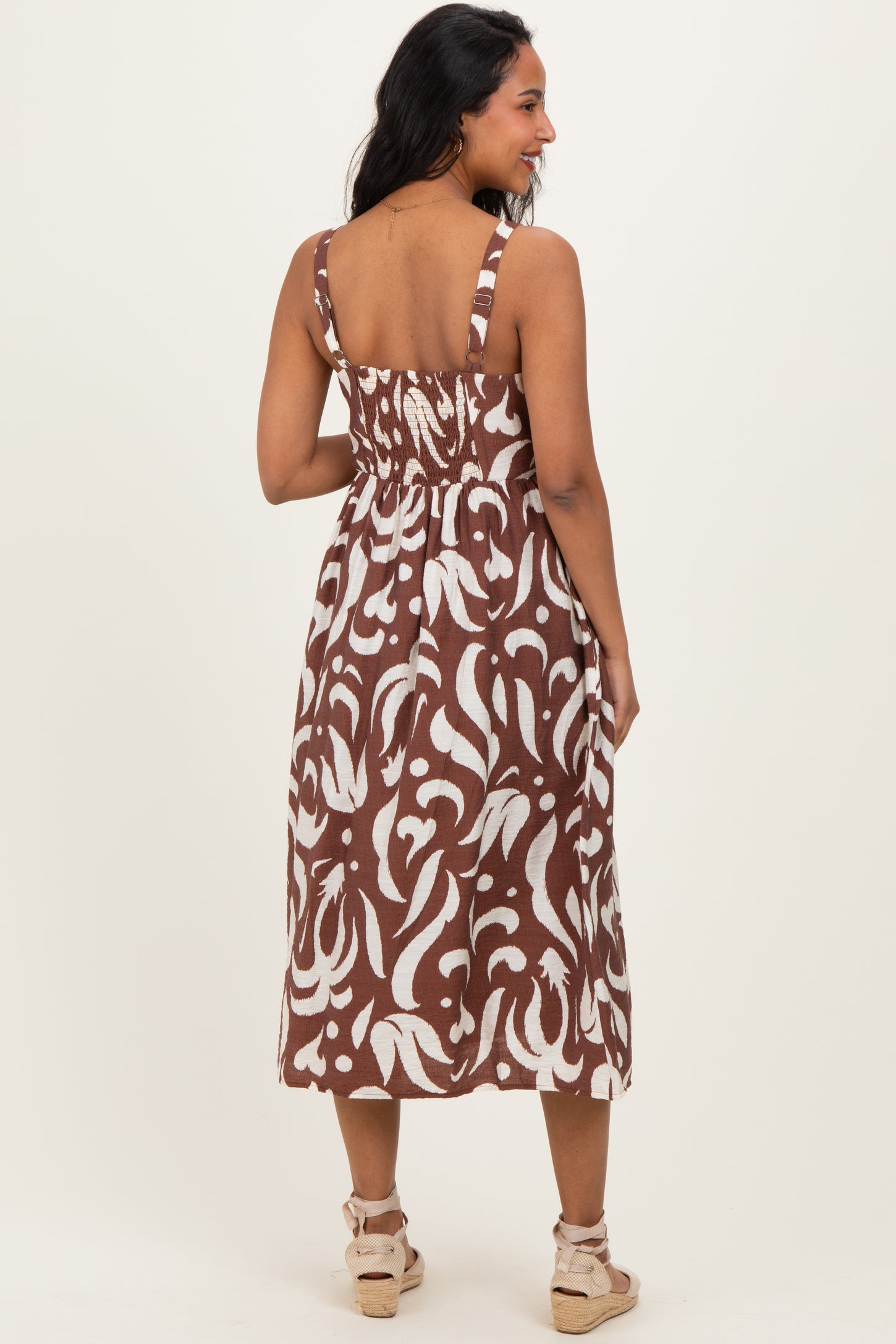 woman wearing a brown and white patterned maternity dress with adjustable straps and a fitted bodice