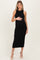 woman wearing a black ribbed maternity dress, holding her baby bump, with heels on