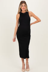 woman wearing a black ribbed midi maternity dress, posing with one hand on her hip and a visible baby bump