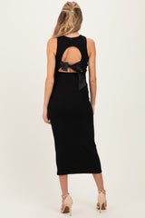 woman wearing a black maternity dress with a back cutout and bow detail, showcasing a baby bump