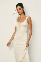 woman wearing a cream colored smocked fitted dress with ruffled straps and a square neckline