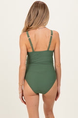 woman wearing a dark green maternity swimsuit with adjustable straps, shown from the back