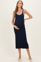 woman wearing a navy blue ribbed maternity dress with white decorative trim and holding her baby bump