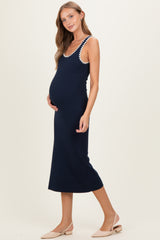 woman wearing a navy blue maternity dress with decorative straps and a visible baby bump