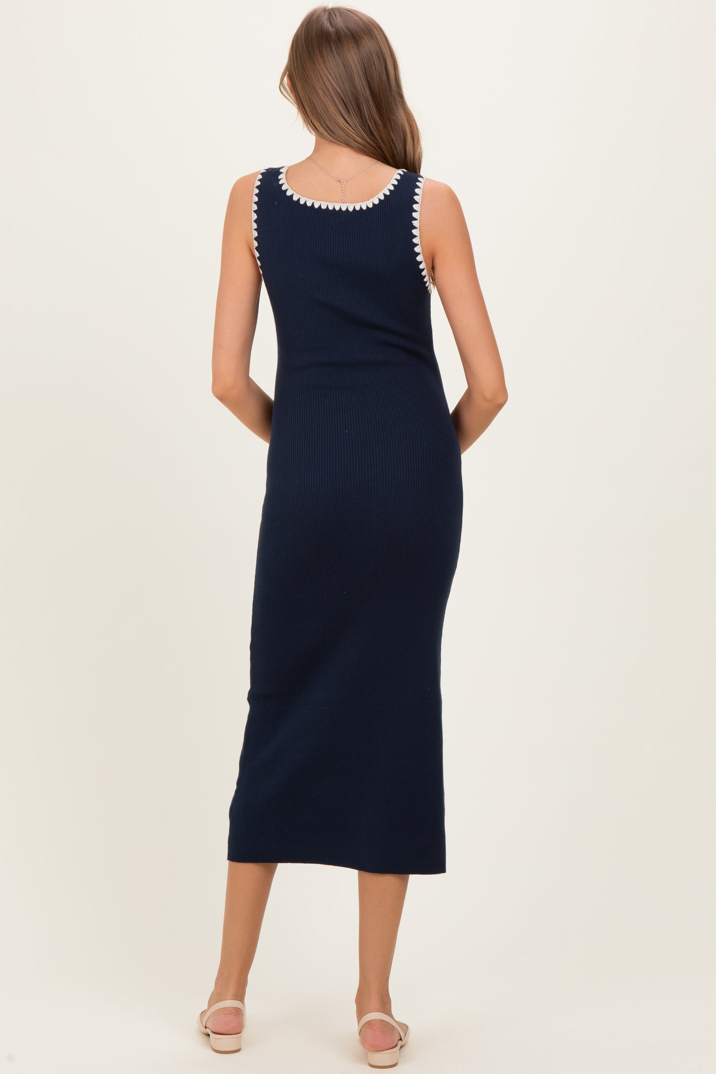 woman wearing a navy blue ribbed maternity maxi dress with white trim detailing on the neckline and shoulder straps