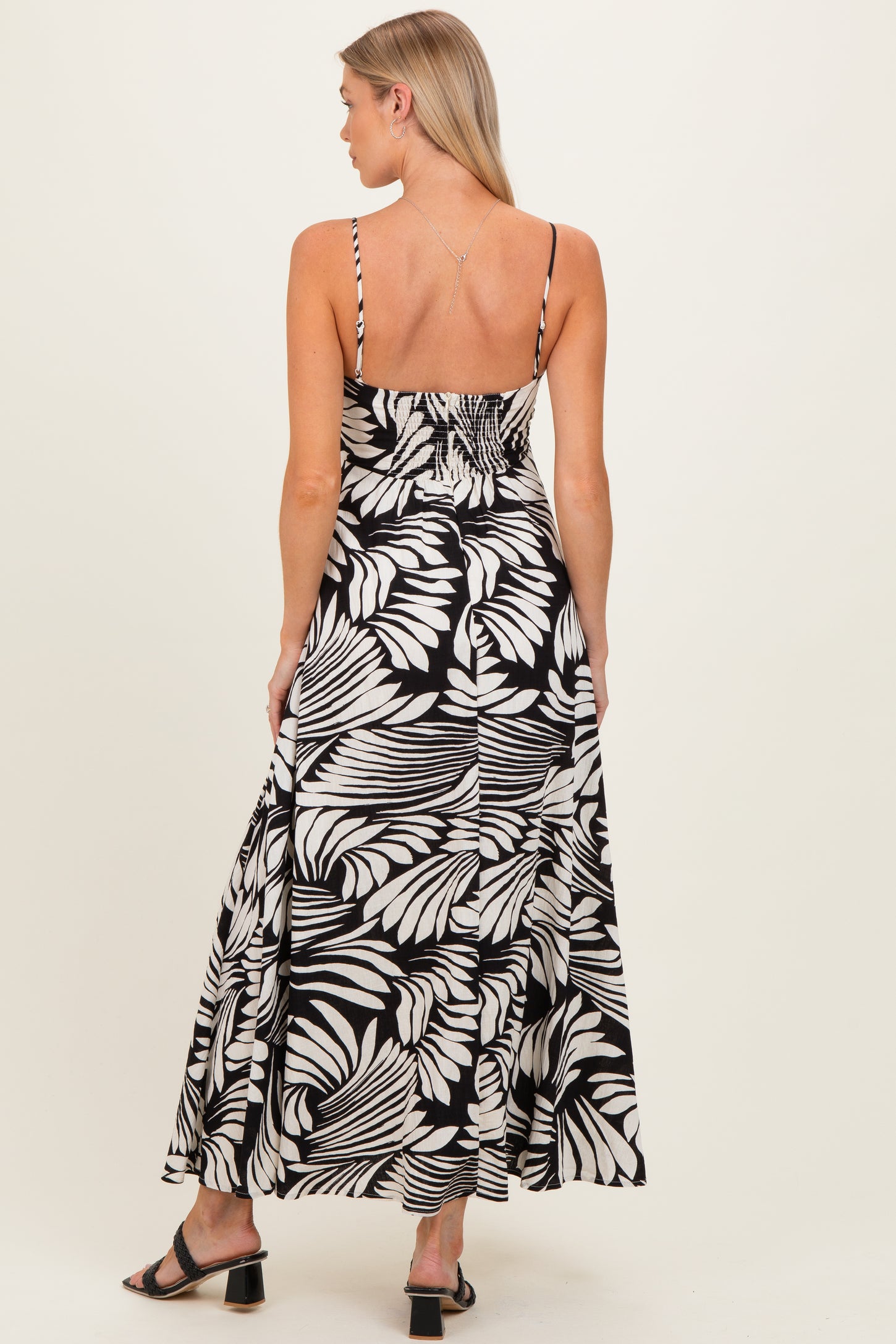 woman wearing a black and white floral maternity maxi dress with spaghetti straps and a fitted bodice