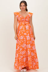 woman wearing an orange floral maternity maxi dress with a smocked bodice and ruffle sleeves, showcasing her baby bump