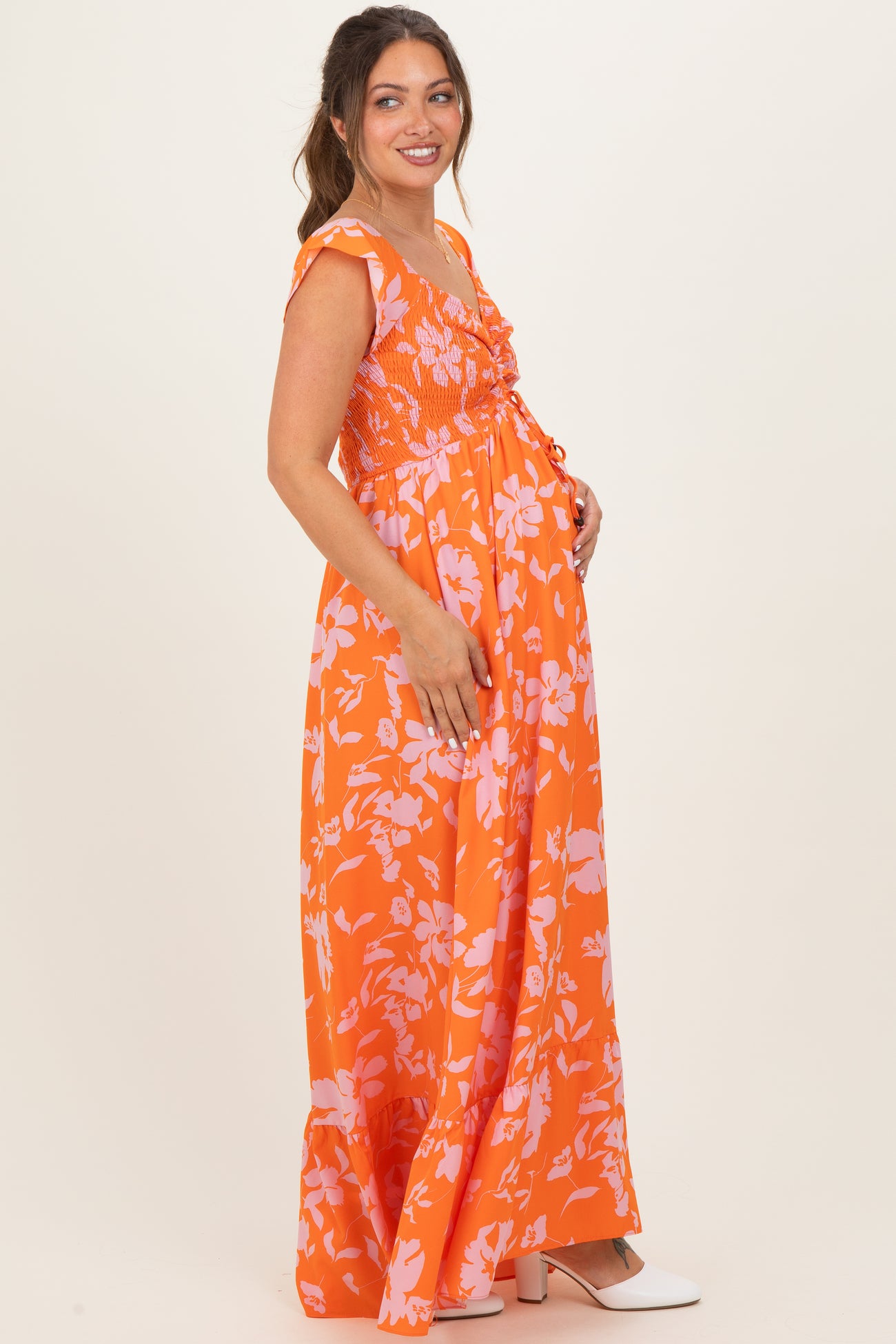 woman wearing an orange floral maternity maxi dress and holding her baby bump