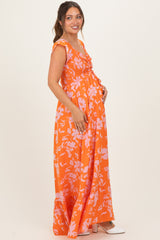 woman wearing an orange floral maternity maxi dress and holding her baby bump
