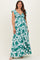 woman wearing a green and white floral maternity maxi dress with a cinched waist and flutter sleeves, showcasing her baby bump