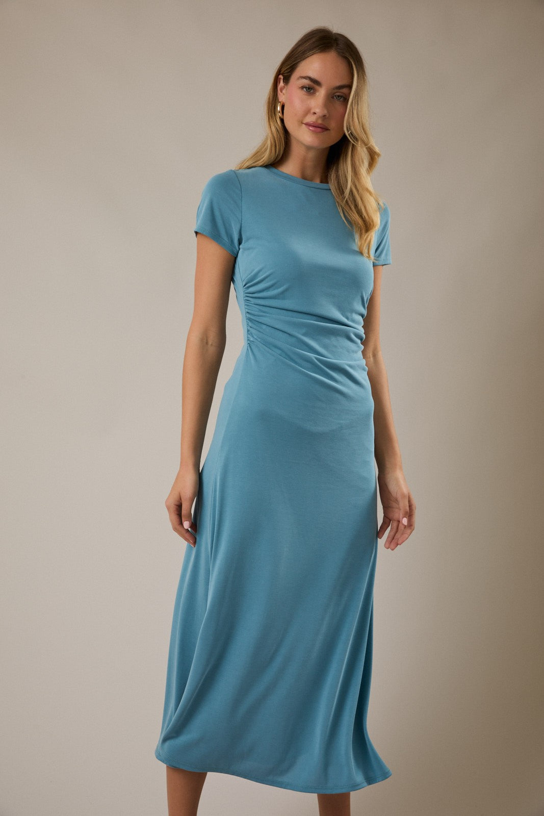 woman wearing a teal short sleeve midi dress with ruching details on the side