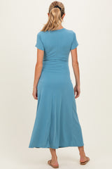 woman wearing a teal short sleeve maternity dress, showing a flowing skirt from the back, casual style