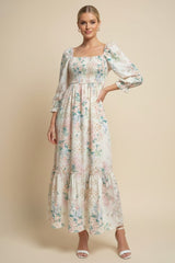 woman wearing a long floral print maxi dress with puff sleeves and a tiered skirt