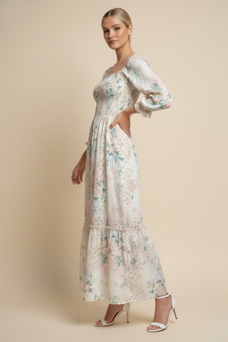 woman wearing a long white floral maxi dress with puff sleeves and a tiered skirt