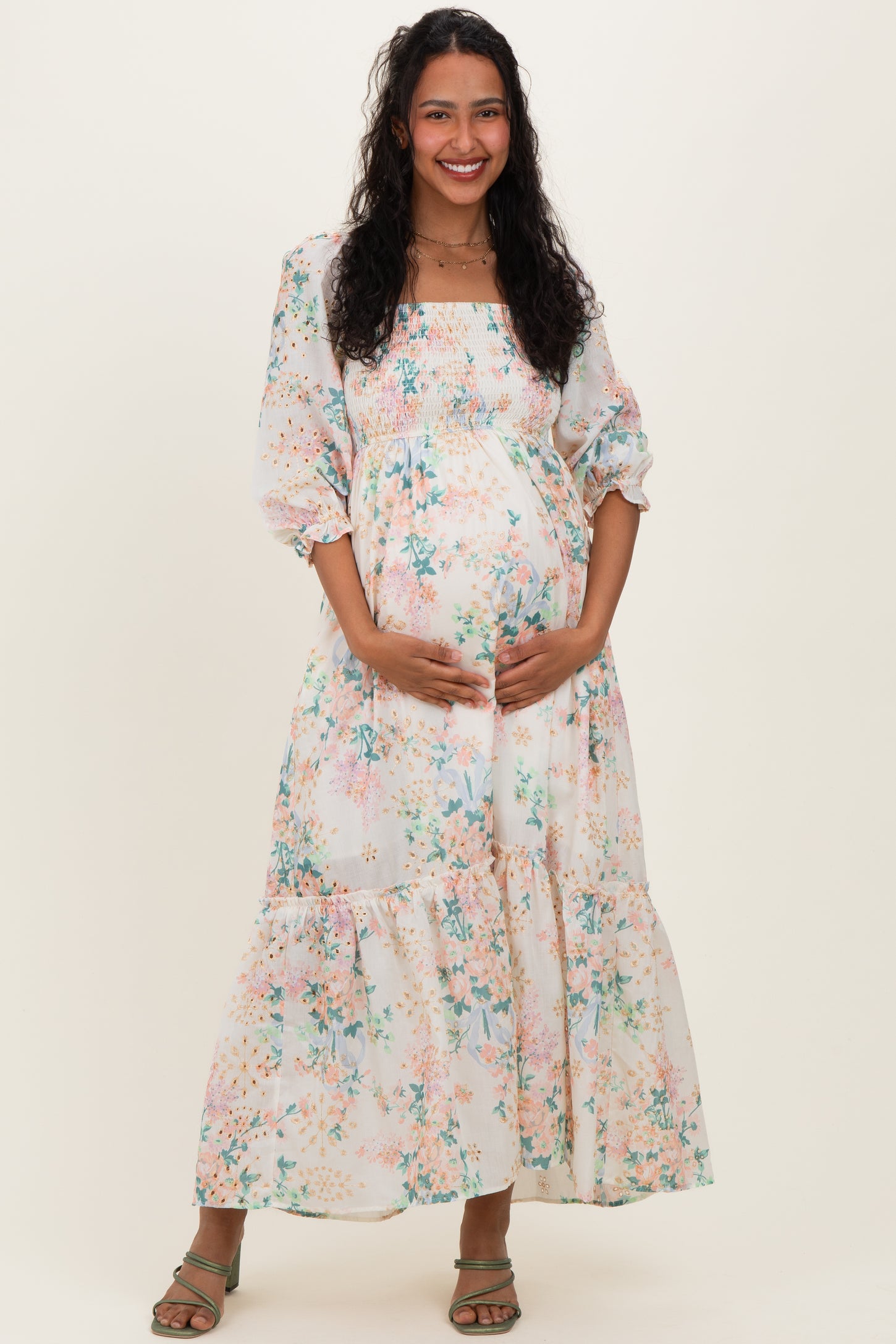 woman wearing a floral maternity maxi dress with balloon sleeves and holding her baby bump