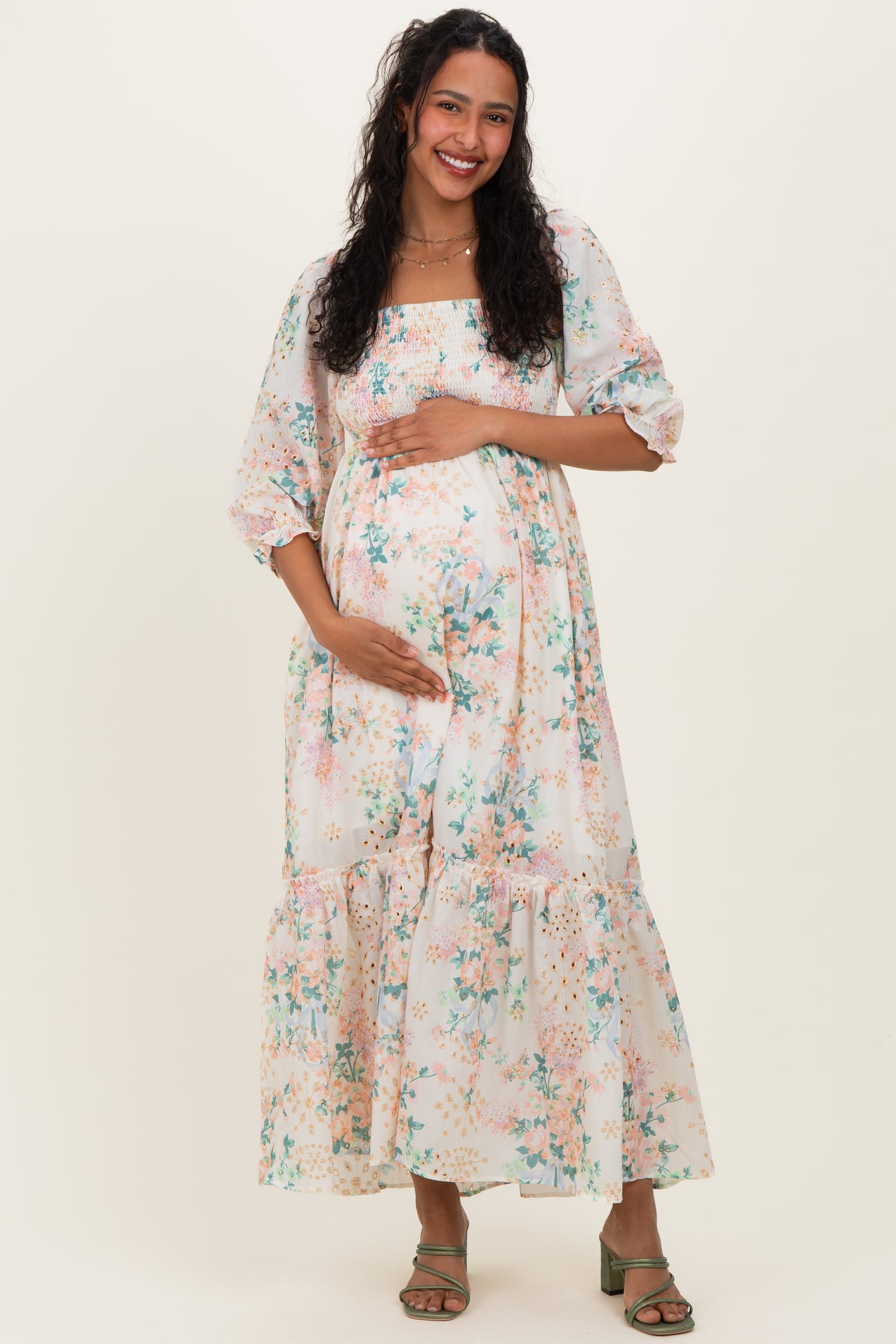 woman wearing a floral print maternity maxi dress with puff sleeves, holding her baby bump