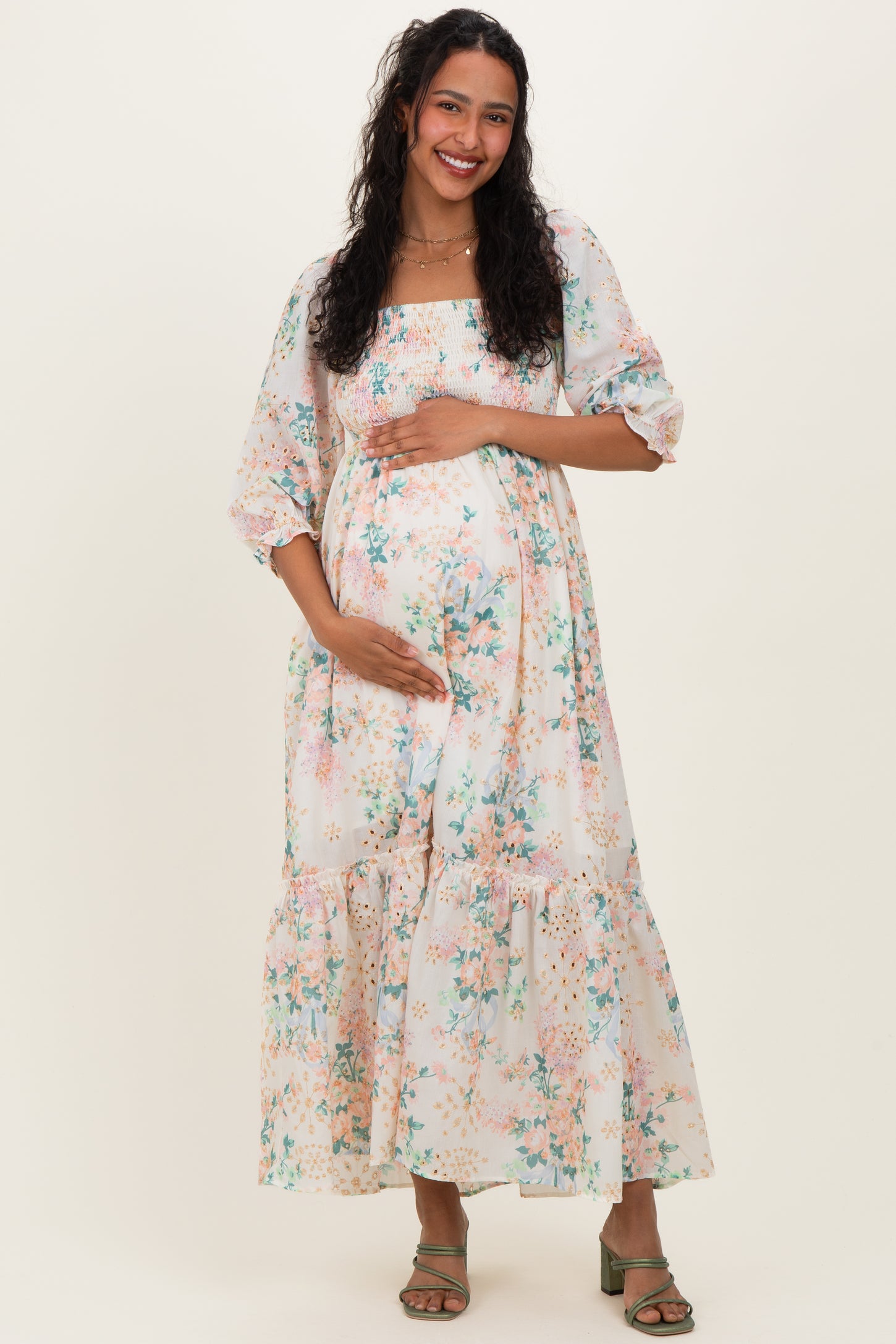 woman wearing a floral print maternity maxi dress with puff sleeves, holding her baby bump