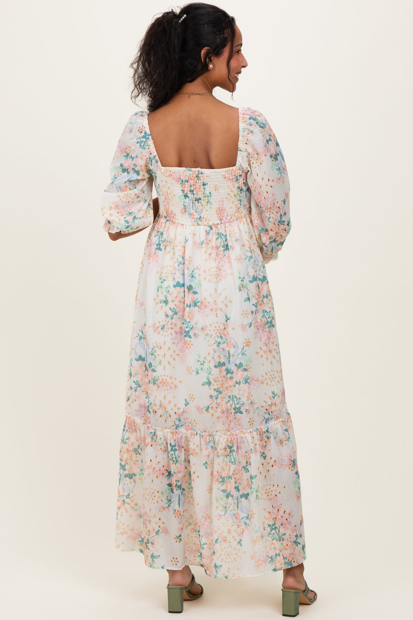 woman wearing a floral print maternity maxi dress with puff sleeves and smocked bodice, showing a baby bump