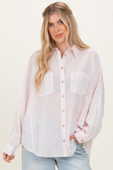 woman wearing a light pink oversized button-up shirt with two chest pockets and rolled-up sleeves