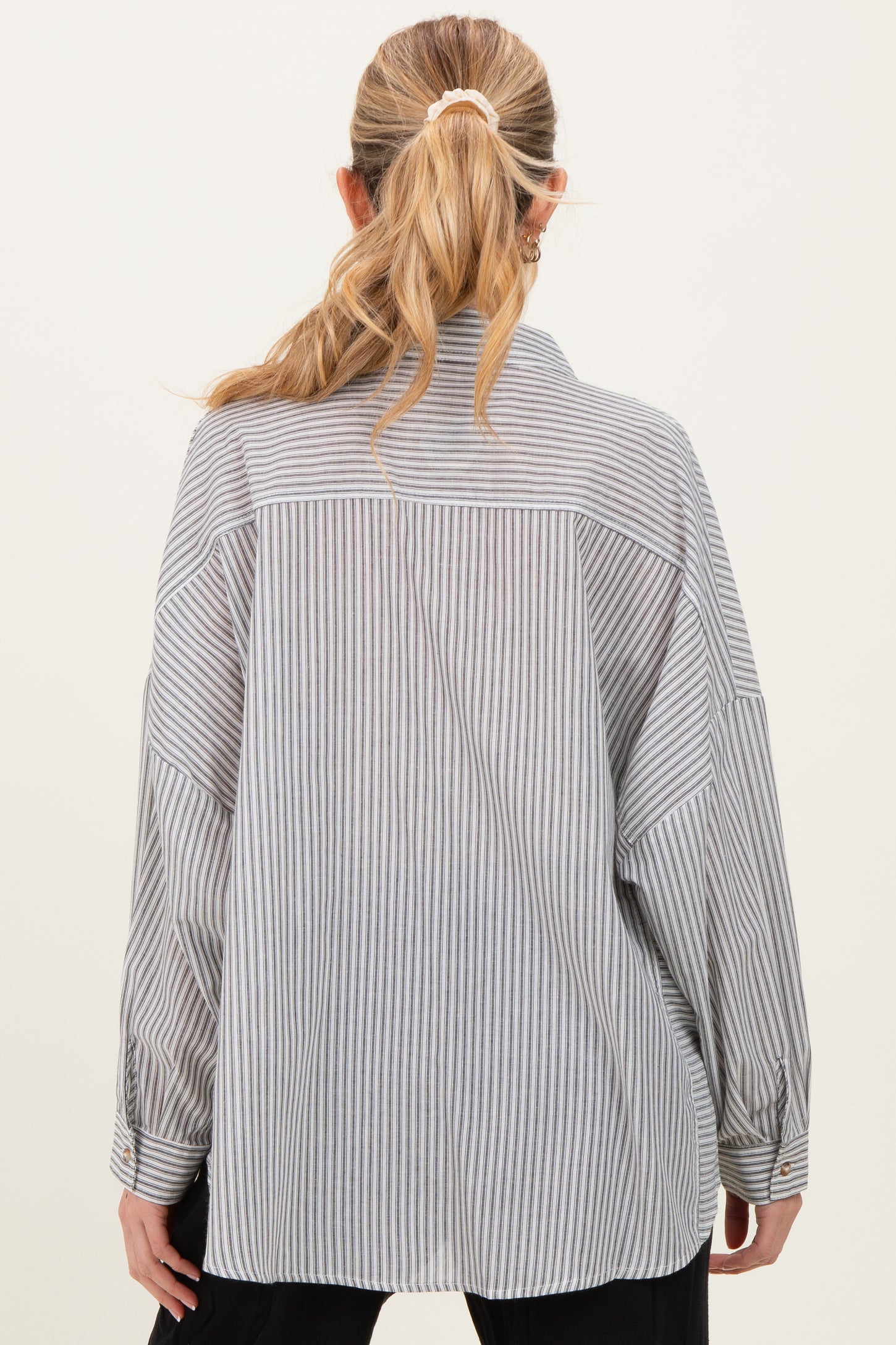 woman wearing a striped maternity shirt featuring a relaxed fit and long sleeves, shown from the back