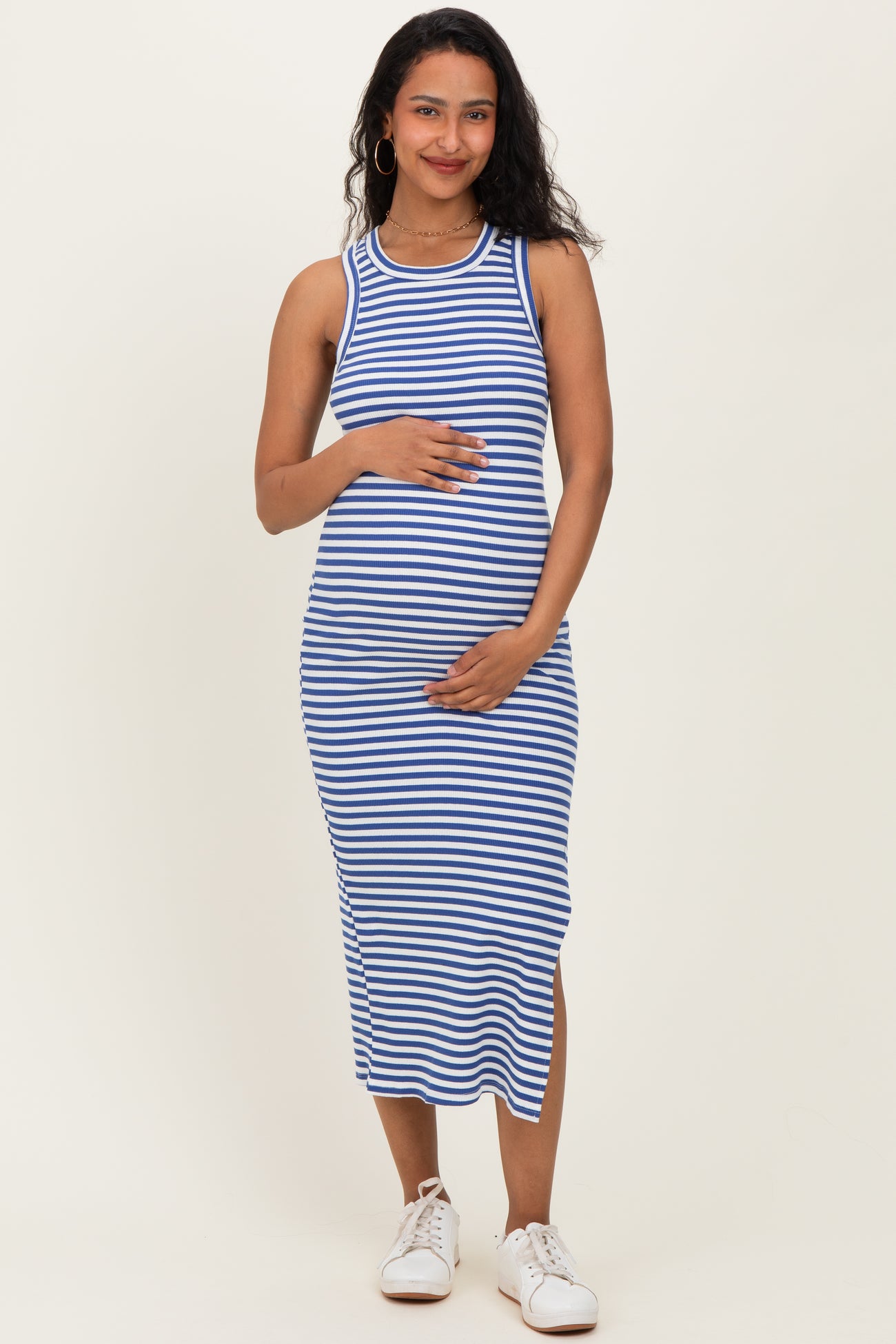 woman wearing a blue and white striped maternity dress with a fitted style and holding her baby bump