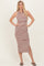 woman wearing a striped sleeveless midi dress in brown and white with a side slit and standing in a relaxed pose