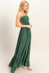 woman wearing a dark green maxi dress with a smocked bodice and ruffled hem, styled with strappy cutout details