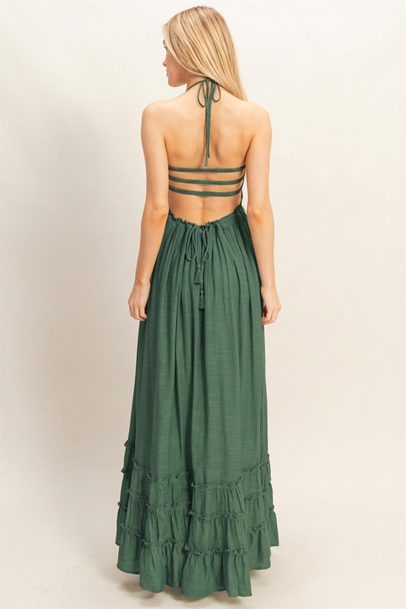 woman wearing a green tiered maxi dress with a halter neck and open back design