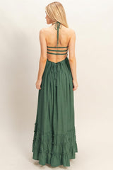 woman wearing a green tiered maxi dress with a halter neck and open back design