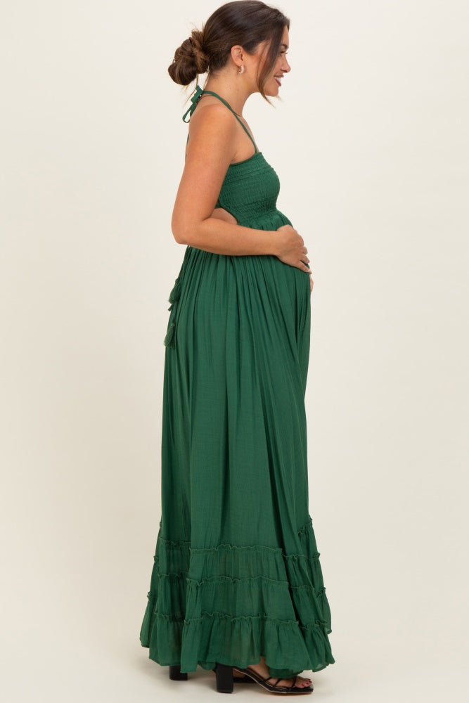 woman wearing a long green maternity maxi dress with a smocked bodice, holding her baby bump