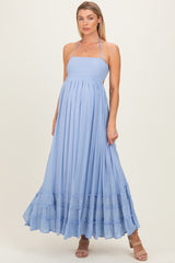 woman wearing a light blue maternity maxi dress with a smocked bodice and ruffled hem, showing her baby bump