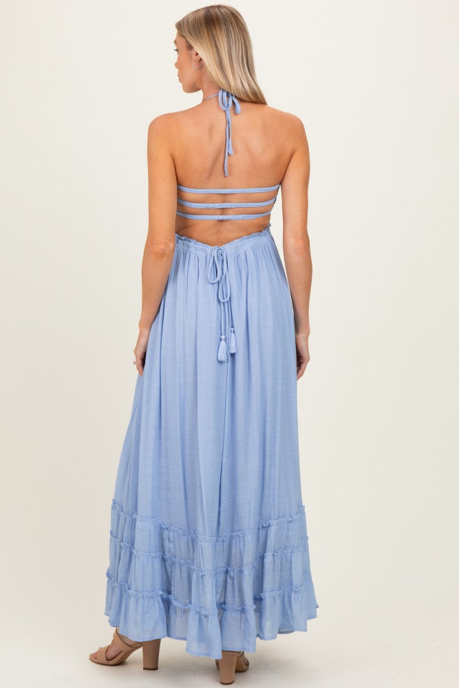 woman wearing a light blue maternity maxi dress with a halter neck and tiered ruffle hem, showing off her baby bump from the back