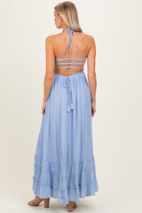 woman wearing a light blue maternity maxi dress with a halter neck and tiered ruffle hem, showing off her baby bump from the back