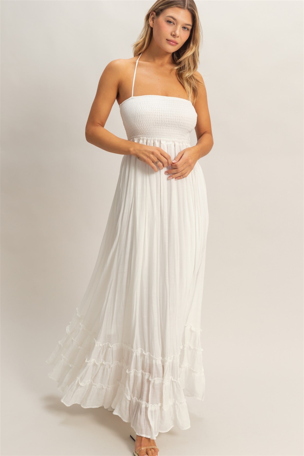 woman wearing a white strapless maxi dress with a smocked bodice and tiered ruffle hem