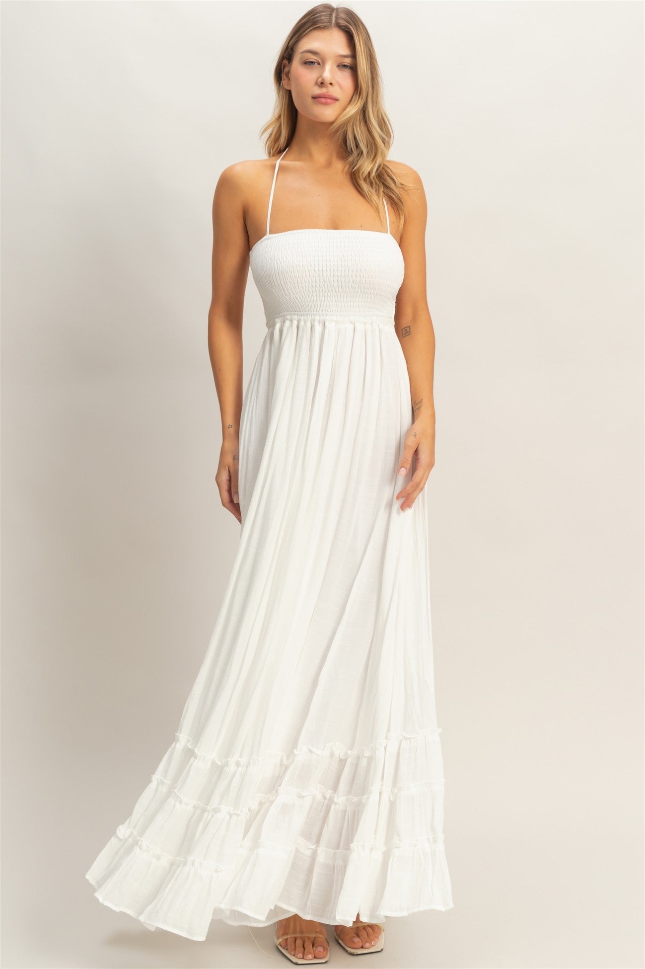 woman wearing a white strapless maxi dress with a smocked bodice and tiered ruffle hem
