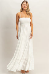 woman wearing a white strapless maxi dress with a smocked bodice and tiered ruffle hem