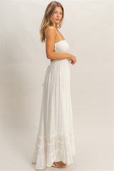 woman wearing a white maxi dress with straps, smocked bodice, and tiered ruffle hem.